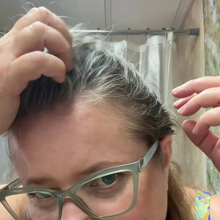 A woman working Polar Shampoo into her gray roots